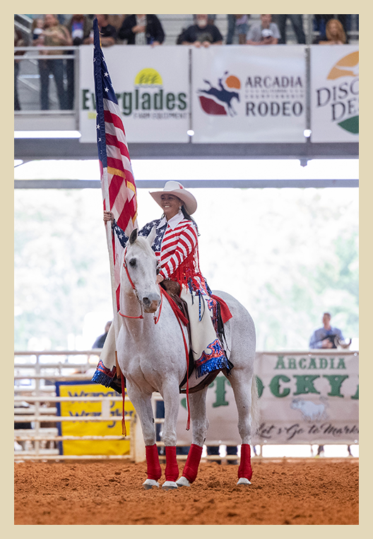 Woman riding on horse holding the american flag